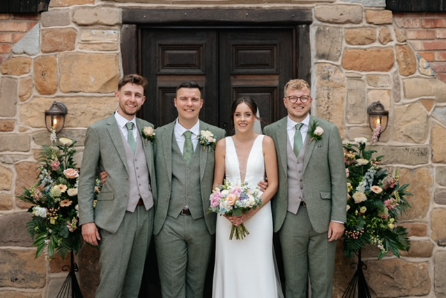 Bride and groomsmen in sage green three-piece suits hired from Scotney’s of London Road